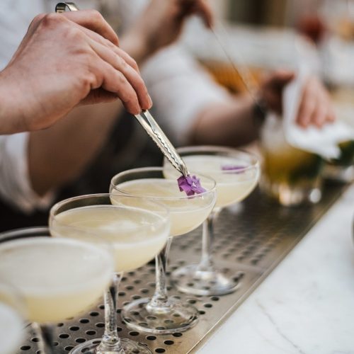 A closeup shot of a barman making margaritas with five glasses set in line