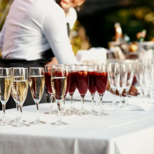 Glasses with red and white wine stand on the white dinner table outside